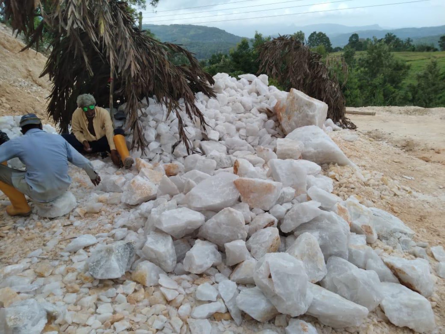 Quartz boulder pile with workers at the family operation